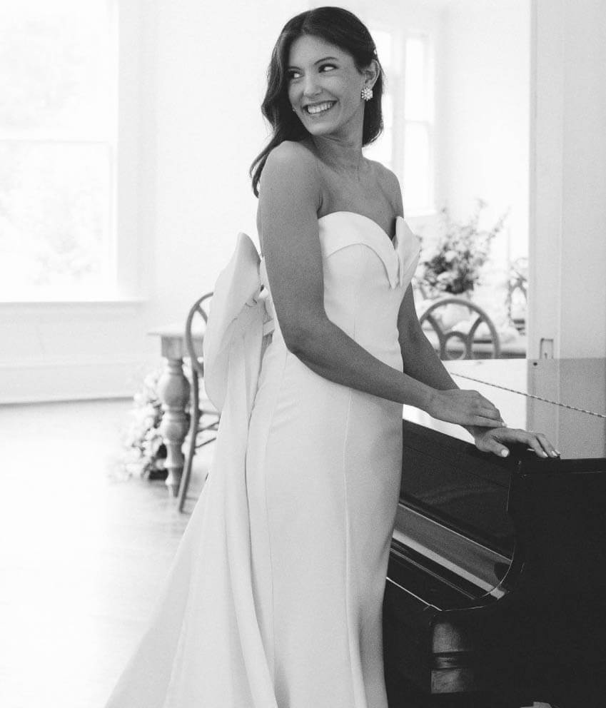 Model wearing a white dress near the piano